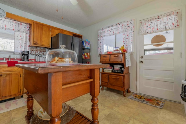 kitchen featuring stainless steel refrigerator, ceiling fan, light tile patterned floors, and a textured ceiling