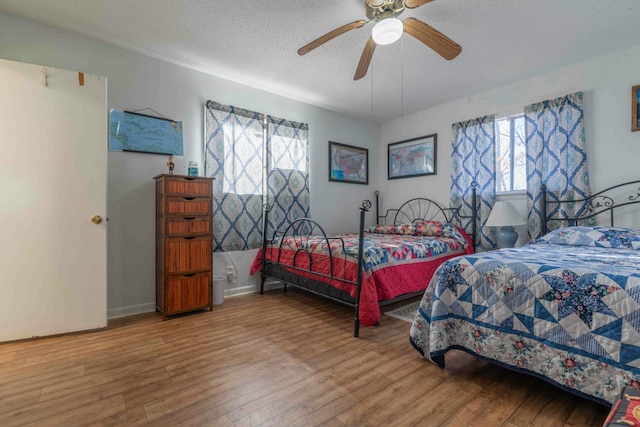 bedroom with hardwood / wood-style flooring, ceiling fan, and multiple windows