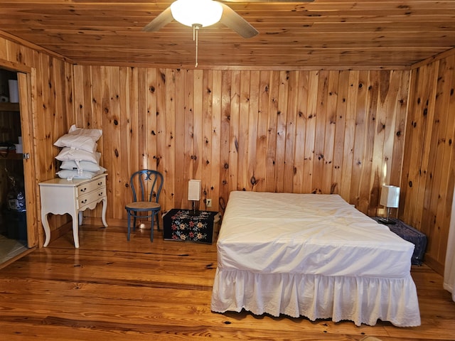 bedroom featuring wood walls, wood finished floors, wood ceiling, and a ceiling fan