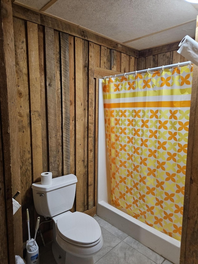 bathroom with toilet, a stall shower, wooden walls, and tile patterned floors