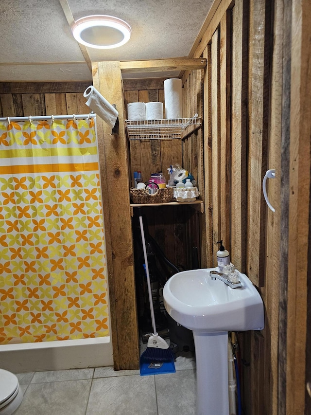 full bathroom featuring toilet, a stall shower, tile patterned flooring, and a textured ceiling