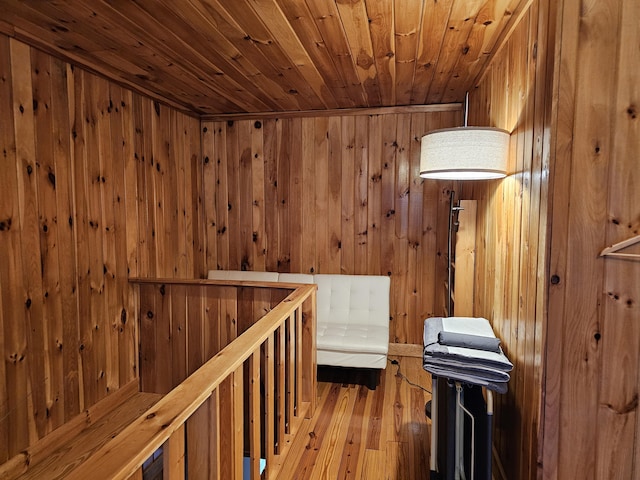 corridor with wooden ceiling, wood walls, wood finished floors, and an upstairs landing