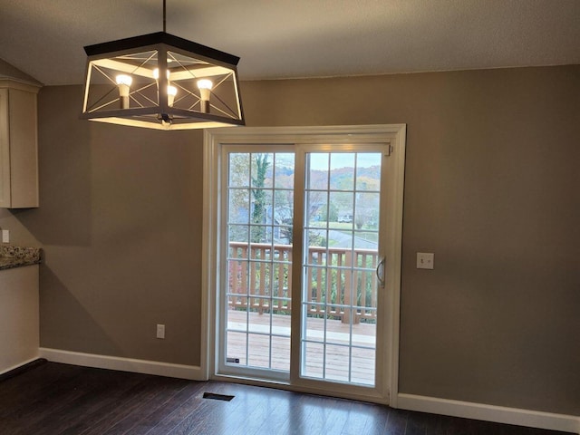 unfurnished dining area with a chandelier and dark hardwood / wood-style floors