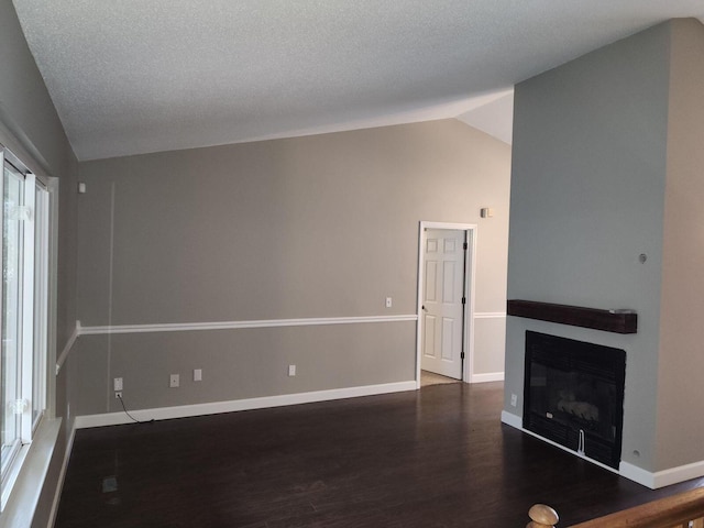 unfurnished living room featuring dark hardwood / wood-style flooring, a textured ceiling, and vaulted ceiling