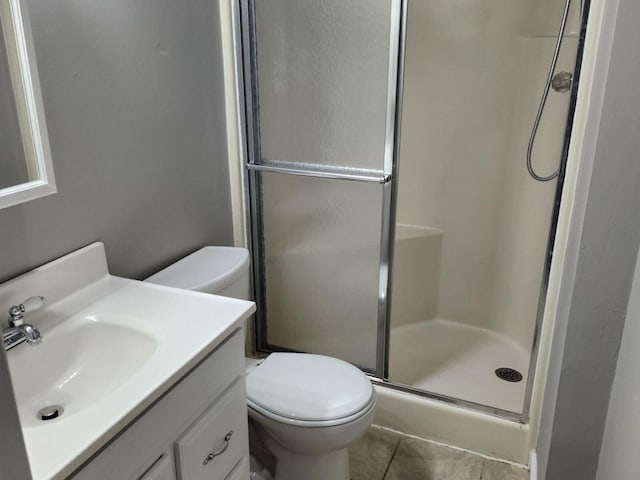 bathroom with tile patterned flooring, vanity, toilet, and a shower with door