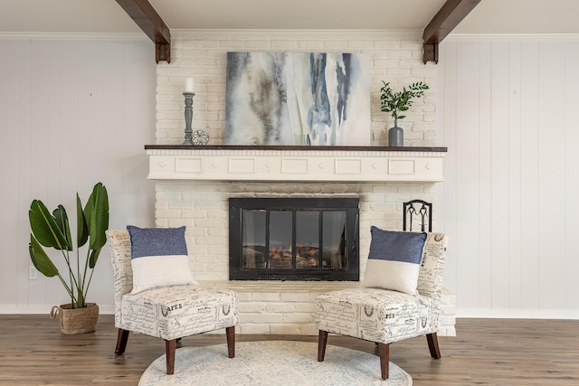 living area with beam ceiling, crown molding, dark hardwood / wood-style flooring, and a brick fireplace