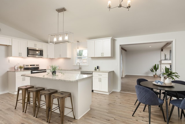 kitchen featuring white cabinets, pendant lighting, light wood-type flooring, and appliances with stainless steel finishes