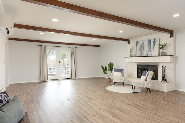 living area with a wall mounted air conditioner, french doors, a brick fireplace, light wood-type flooring, and beam ceiling