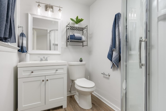 bathroom with toilet, vanity, a shower with shower door, and hardwood / wood-style flooring