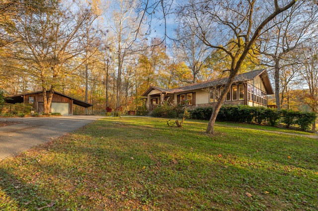 ranch-style home featuring a sunroom, a garage, an outbuilding, and a front yard