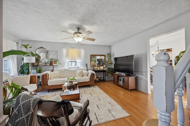 living room featuring ceiling fan, a textured ceiling, and light wood-type flooring