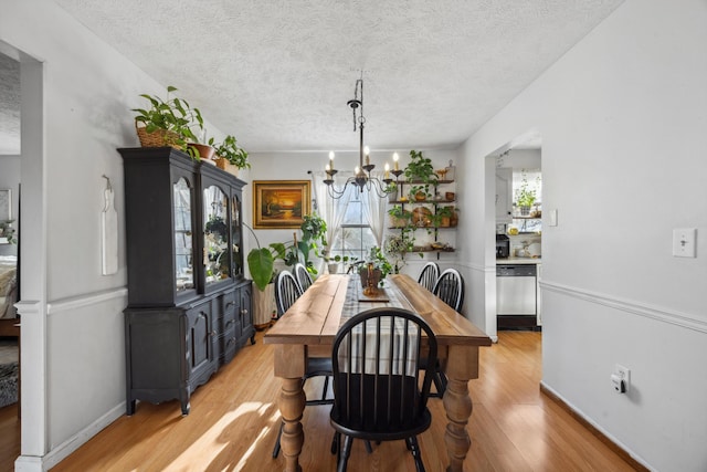 dining room featuring a chandelier, a textured ceiling, and light wood-type flooring