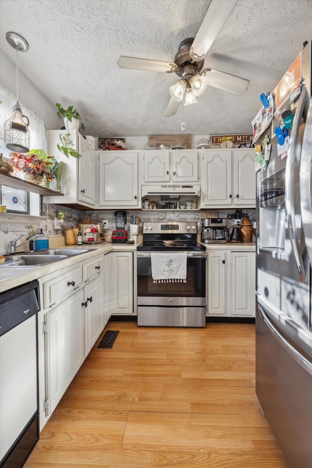 kitchen with white cabinetry, hanging light fixtures, stainless steel appliances, light hardwood / wood-style flooring, and backsplash