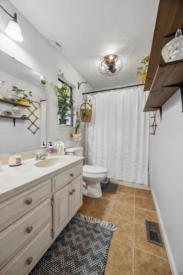 bathroom featuring toilet, vanity, a textured ceiling, and tile patterned floors