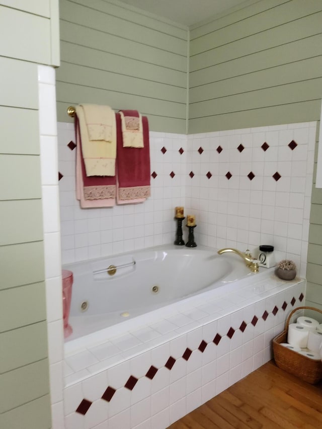 bathroom featuring wood-type flooring and tiled tub