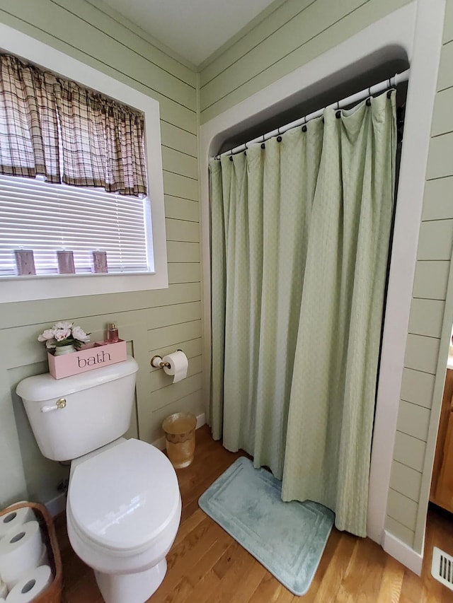 bathroom featuring toilet, wooden walls, hardwood / wood-style floors, and a shower with shower curtain