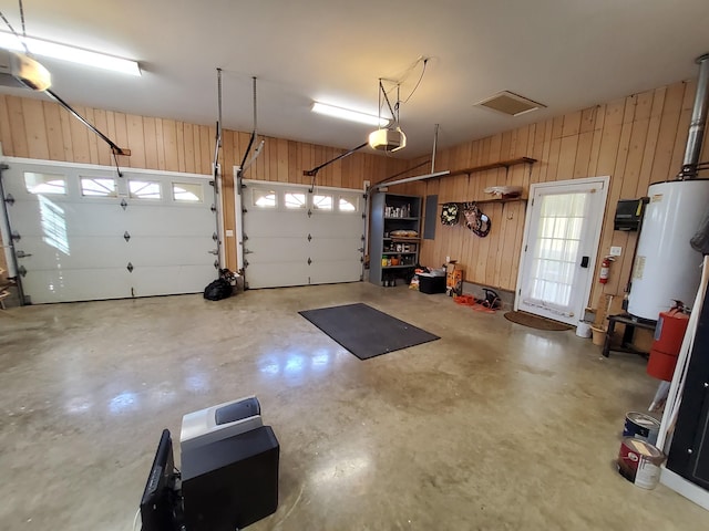 garage with wood walls, gas water heater, and a garage door opener