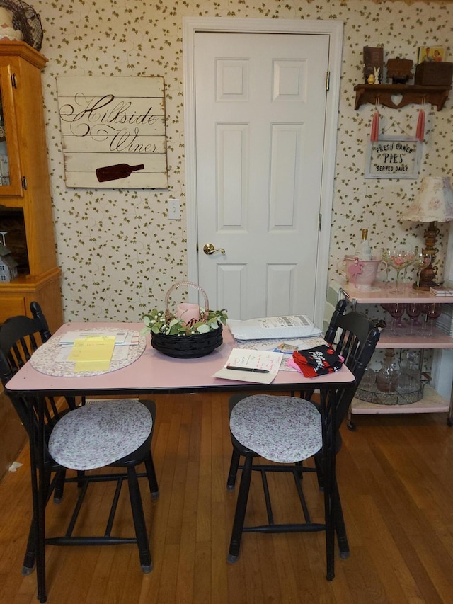 dining area featuring dark wood-type flooring and wallpapered walls