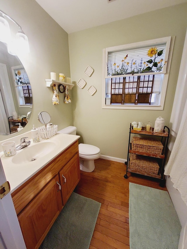 bathroom with toilet, wood finished floors, vanity, and baseboards