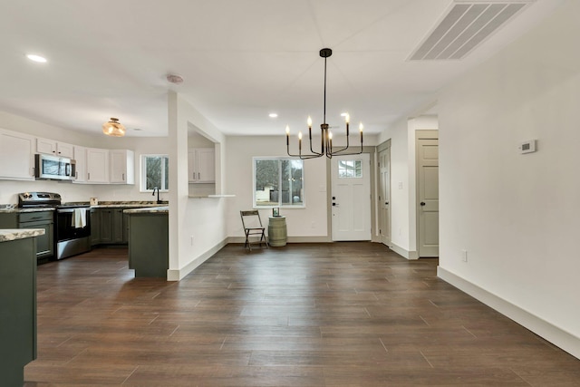 kitchen featuring a notable chandelier, appliances with stainless steel finishes, white cabinets, dark wood-type flooring, and pendant lighting