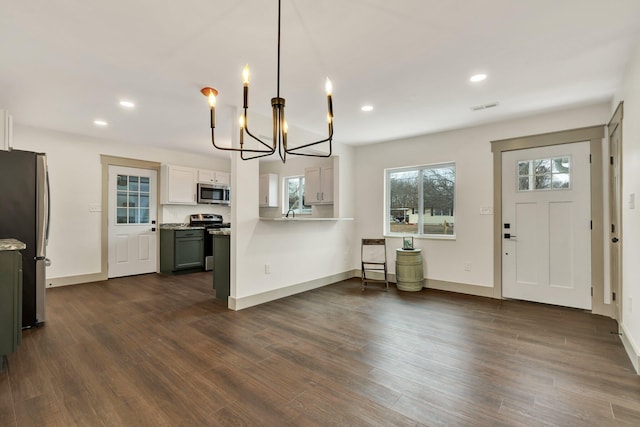 kitchen featuring dark hardwood / wood-style flooring, decorative light fixtures, white cabinetry, a notable chandelier, and stainless steel appliances