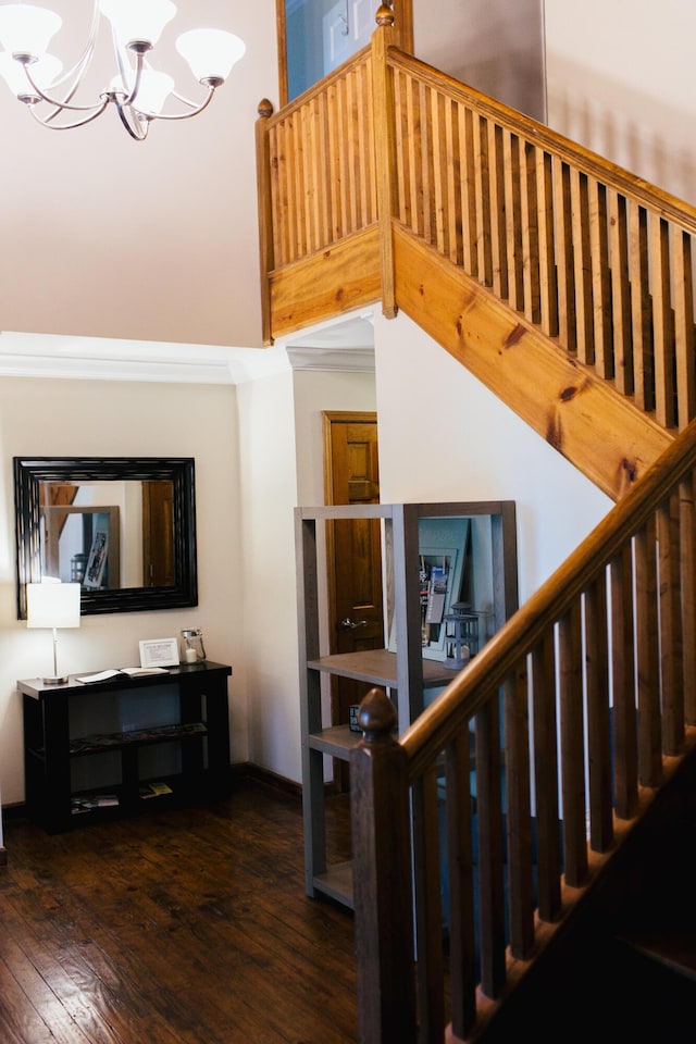 staircase with hardwood / wood-style flooring, a towering ceiling, and an inviting chandelier