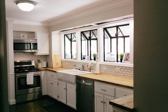 kitchen with butcher block counters, sink, stainless steel appliances, backsplash, and white cabinets