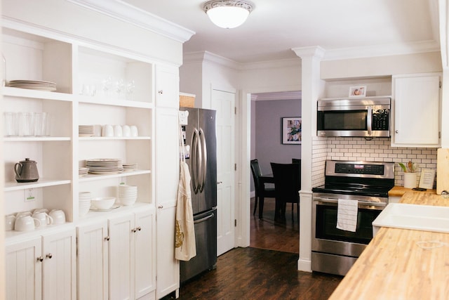 kitchen featuring dark hardwood / wood-style flooring, wooden counters, appliances with stainless steel finishes, white cabinets, and ornamental molding