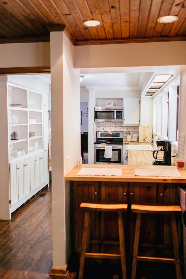 kitchen featuring decorative backsplash, appliances with stainless steel finishes, dark hardwood / wood-style floors, and wood ceiling