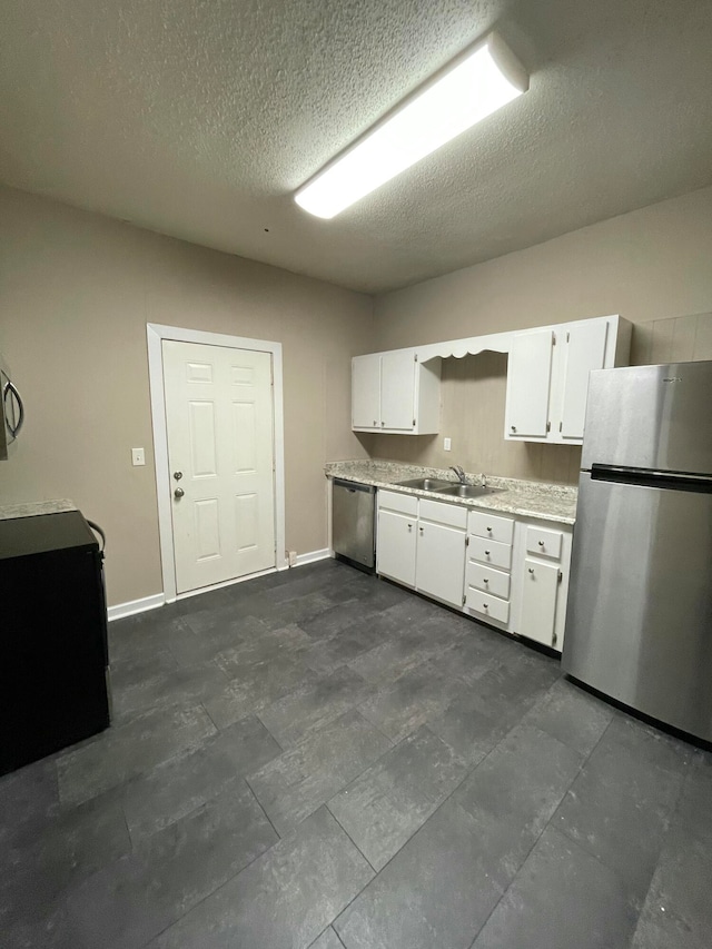 kitchen featuring appliances with stainless steel finishes, a textured ceiling, white cabinetry, and sink