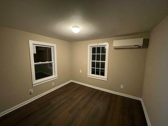 spare room featuring a wall mounted air conditioner and dark hardwood / wood-style floors