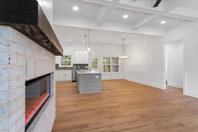 kitchen featuring white cabinets, stainless steel dishwasher, light wood-type flooring, decorative light fixtures, and a kitchen island