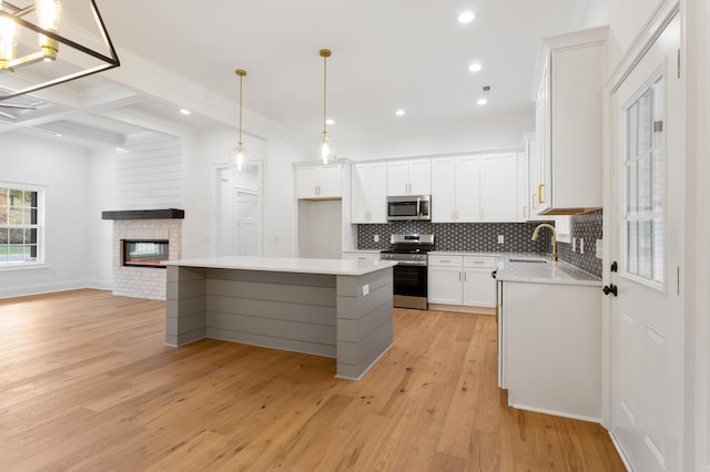 kitchen with white cabinetry, sink, a center island, light hardwood / wood-style flooring, and appliances with stainless steel finishes