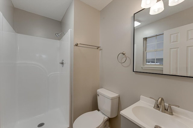 bathroom with a shower, vanity, a textured ceiling, and toilet