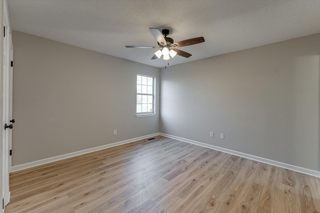 spare room with a textured ceiling, light wood-type flooring, and ceiling fan