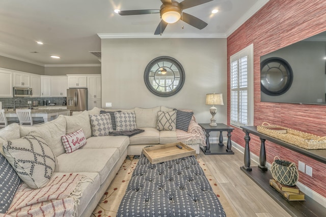 living room featuring sink, light hardwood / wood-style flooring, ornamental molding, and ceiling fan