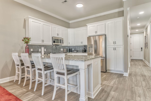 kitchen with backsplash, stainless steel appliances, light stone countertops, and white cabinets