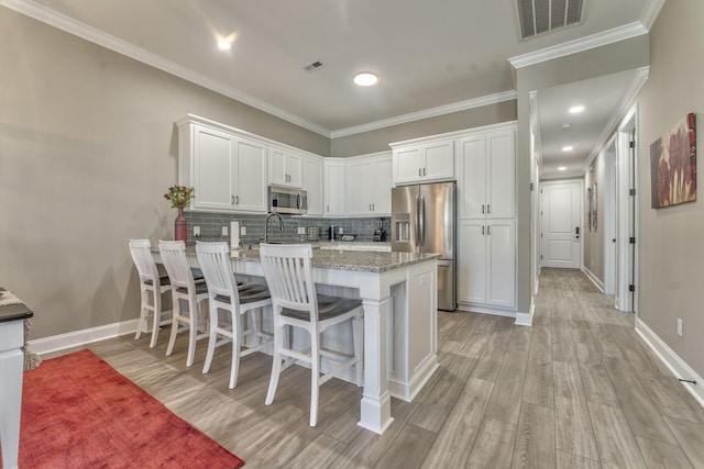 kitchen with stainless steel appliances, light stone counters, white cabinets, decorative backsplash, and kitchen peninsula