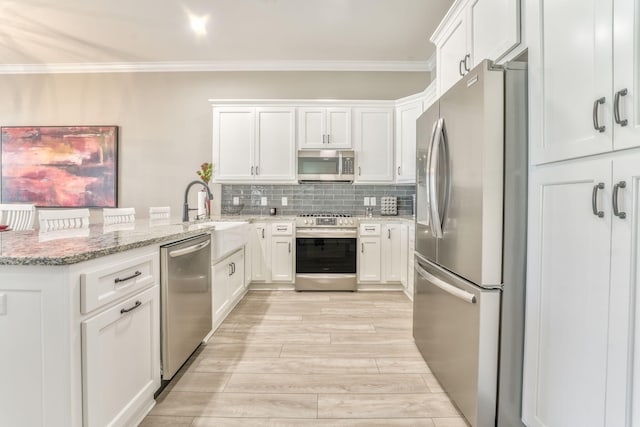 kitchen with sink, light stone counters, crown molding, appliances with stainless steel finishes, and white cabinets