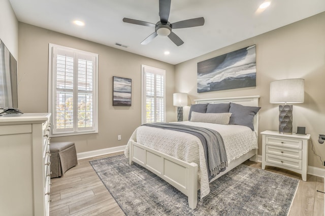 bedroom featuring ceiling fan, multiple windows, and light hardwood / wood-style flooring