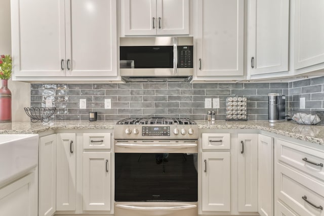 kitchen with tasteful backsplash, appliances with stainless steel finishes, and white cabinets