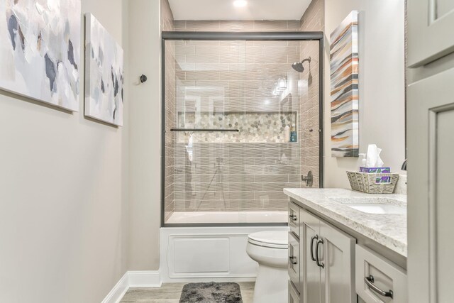 full bathroom featuring hardwood / wood-style flooring, vanity, toilet, and combined bath / shower with glass door