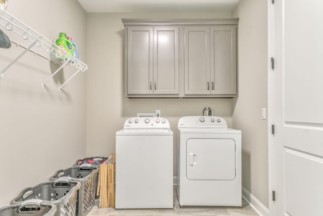 clothes washing area with washing machine and dryer and cabinets