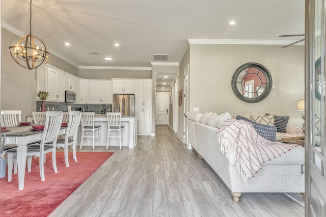 dining space with crown molding, light hardwood / wood-style flooring, and a chandelier