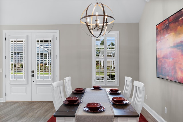 dining area featuring hardwood / wood-style floors, an inviting chandelier, and french doors