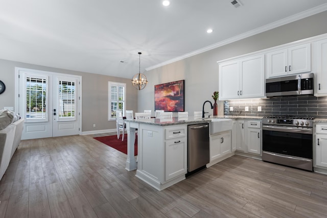 kitchen with hanging light fixtures, white cabinetry, appliances with stainless steel finishes, and kitchen peninsula