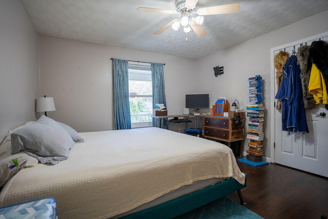 bedroom with a textured ceiling, ceiling fan, dark wood-type flooring, and a closet