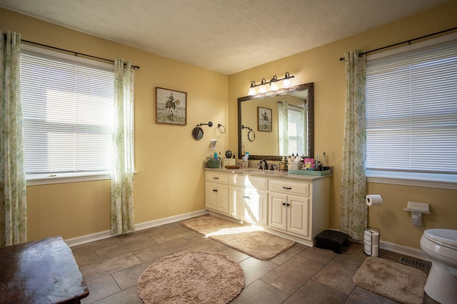 bathroom with tile patterned flooring, a textured ceiling, vanity, and toilet