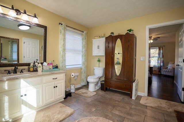 bathroom with wood-type flooring, vanity, toilet, and ceiling fan