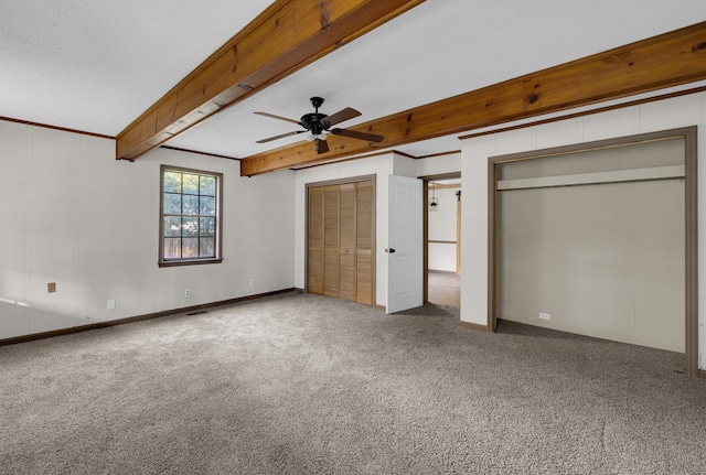 unfurnished bedroom with ceiling fan, beam ceiling, carpet floors, and ornamental molding